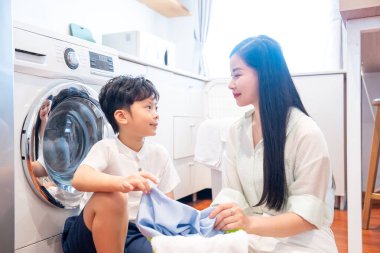 Arka planda çamaşır makinesi çalışan bir anne ve oğlu vardı.