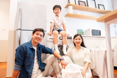 Üç kişilik neşeli bir aile çamaşırlarını birlikte yıkıyor. Parlak, modern bir mutfak ortamında.