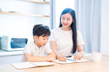 Bir anne, çocuğunun okul masraflarına yardım eder. Parlak bir masada öğrenmesini sağlar.