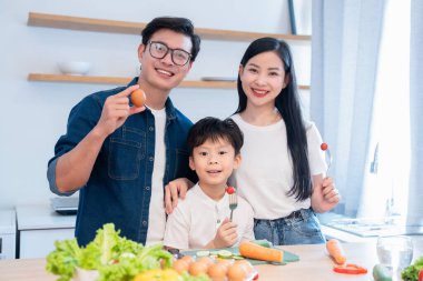 Mutlu bir aile modern mutfağında sağlıklı bir yemek için taze sebze ve yumurta hazırlıyor.