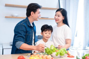 Bir aile, parlak modern mutfaklarında renkli bir salata hazırlayıp sağlıklı alışkanlıklar edinmeyi sever.
