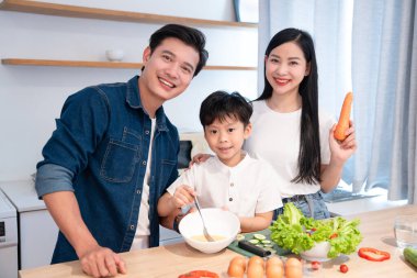 Parlak bir mutfakta mutlu bir aile yemeği. Taze bir yemekle birlikte sağlık ve birlikteliği teşvik ediyor.