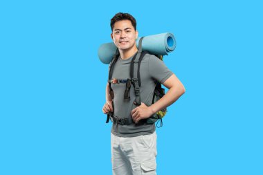 Sırt çantalı bir adam açık hava macerasına hazır gülümsüyor ve elleri kalçasında yolculuk için.