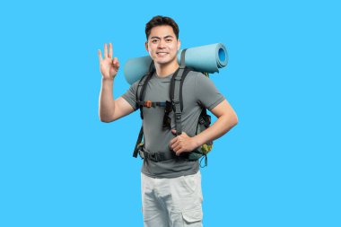 Sırt çantası takmış, gülümseyen coşkulu yürüyüşçü mavi arka planda 