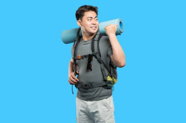 Sırt çantasıyla kamp yapmaya ve mavi arka planda yürüyüş yapmaya hazır mutlu bir adam var.