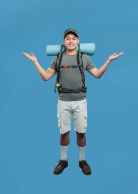 Sırt çantalı ve yürüyüş takımlı gülümseyen bir adam mavi arka planda maceraya hazır.