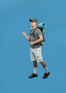 Sırt çantalı bir adam mavi ayara karşı hareket eder Şortu ve şapkası vardır Maceraya hazır