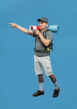 Sırt çantası haritalı ve megafon noktalı bir yürüyüşçü, sağlam mavi bir arkaplan karşısında kendine güvenen bir ifade ile.