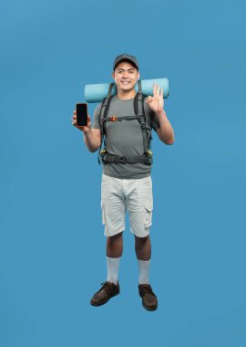 Mutlu yürüyüşçü sırt çantası uyku paspası ve mavi üzerine günlük giysiler. Elinizde telefonla imzalayın.