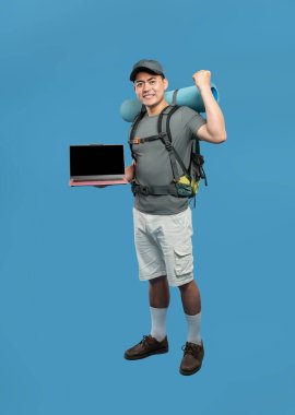 Mavi arka planda açık hava kıyafetleri içinde bir maceraperest heyecanlı bir şekilde dizüstü bilgisayarla zaferi kutluyor.