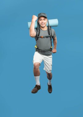 Sırt çantası ve uyku tulumuyla heyecanlı bir yürüyüşçü maceraya hazır parlak mavi bir arka plana atlıyor.