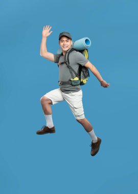 Yürüyüş yaparken mavi bir zeminde coşkuyla zıplayan gülümseyen bir adamın vücut portresi.