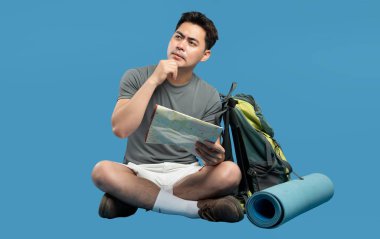 Düşünceli bir yürüyüşçü haritayı incelerken çapraz bacaklı bir sırt çantası ve uyku paspası yakınlardadır.