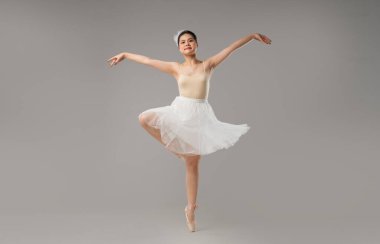 Bir balerin, etek ve diğer şeyleri giyerken stüdyoda dans figürü yapar.