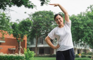 Spor giyim sektöründe gülümseyen bir kadın parka benzer bir ortamda spor ve sağlık ortamını destekliyor.