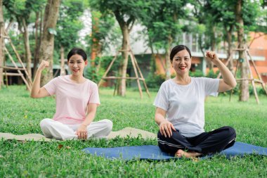 Parktaki iki kadın fiziksel güçlerini dışardaki egzersizleri sırasında esneyerek gösteriyorlar.