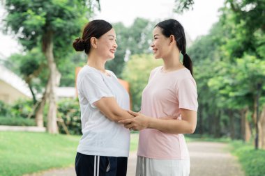 Bir anne ve kızı, bir huzur parkında el ele tutuşup bağlarını göstererek hassas bir anı paylaşıyor.