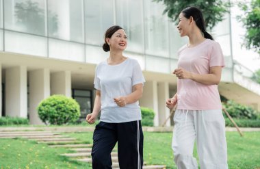 İki kadın parkta koşuyor ve gülümsüyor. Hava güzel ve kadınlar mutlu görünüyor.