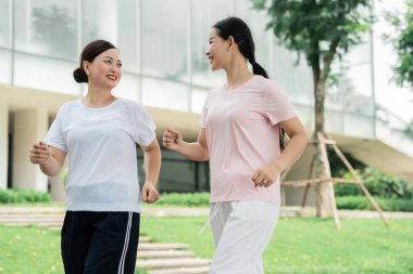 İki kadın yeşil alanlarla çevrili taştan bir yolda yürür hafif egzersiz ve sohbetle meşgul olurlar.