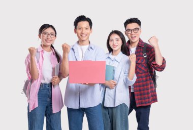 Dört heyecanlı öğrenci, kitaplarla ve klasörlerle poz verirken başarıyı kutlarken gülümsüyor.