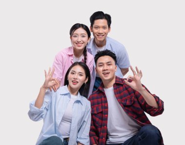 Dört gülümseyen genç yetişkin, tarafsız bir arkaplanda poz veriyor. Tamam jestler, olumlu jestler ve arkadaşlıklar sunuyor.