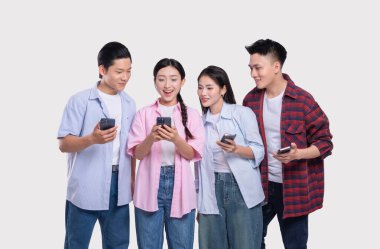 Dört arkadaşından oluşan bir grup telefonlarına dalmış gülümsüyor ve ekranlarına bakıyor.