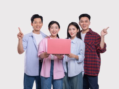 Dört gülümseyen genç yetişkin dizüstü bilgisayarlarını arka planda sağlam renklerde tutarak yukarıya doğru mutlu bir şekilde işaret ediyorlar.