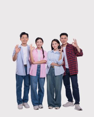 Normal giyinmiş dört yetişkin gülümseyip arka planda izole bir şekilde iyi bir jest yapıyor.