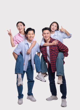 İki gülümseyen genç adam arka planda iki genç bayanı sırtında taşıyor.