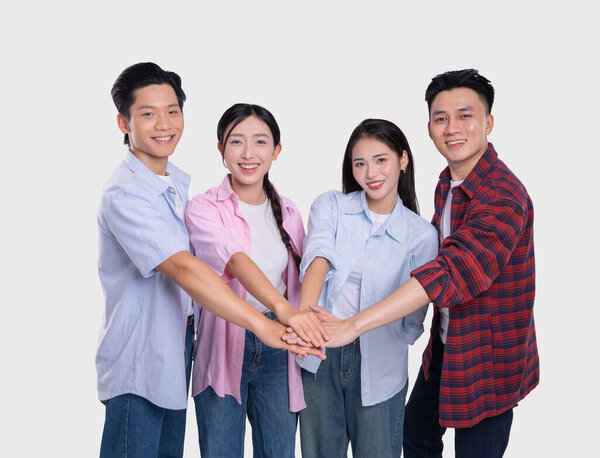 Группа молодых профессионалов взялась за руки, чтобы выразить свою приверженность командной работе и сотрудничеству в студии.