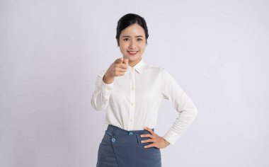 Kendine güvenen, resmi giyinmiş bir kadın kameraya gülümseyen bir şekilde bakıyor.