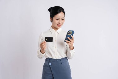 Bir kadının elinde kredi kartı ve akıllı bir telefon vardır. Kolayca internetten alışveriş yapmaya hazırdır.