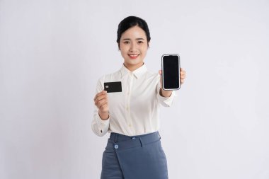 Asyalı bir kadın bir elinde akıllı telefon, diğer elinde kart tutarken gülümser.