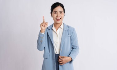 Takım elbiseli gülümseyen bir kadın beyaz bir arkaplan önünde yukarıya doğru işaret ediyor.