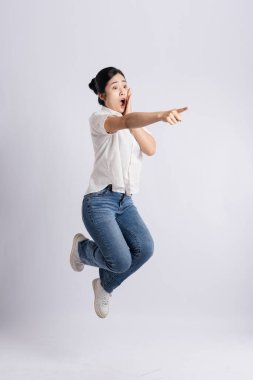 Havanın ortasındaki coşkulu kadın beyaz bir zemine karşı hoş bir şok ifadesi sergiliyor.