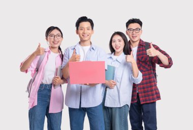 Dört gülümseyen Asyalı öğrenci, ellerinde kitaplarla arka planda durup başparmak kaldırıyorlar.