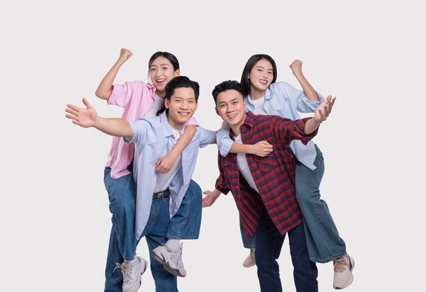 Две азиатские пары радостно празднуют и смеются, катаясь на спине со своими партнерами