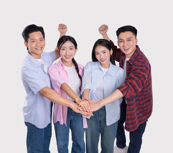 Разнообразная группа из четырех молодых людей празднует успех с руками, сложенными в единстве с улыбками повсюду