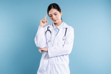 Düşünceli bir tıp çalışanı, sade bir mavi zeminde izole edilmiş tıbbi ortamda çözümler üzerinde kafa yorar.