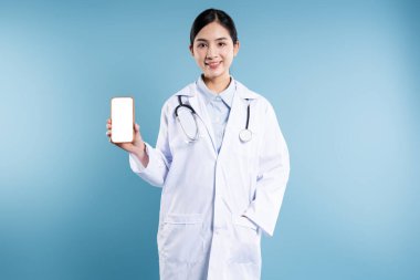 Laboratuvar önlüklü, gülümseyen bir sağlık görevlisi stüdyo ortamında boş ekranlı bir telefon tutuyor.