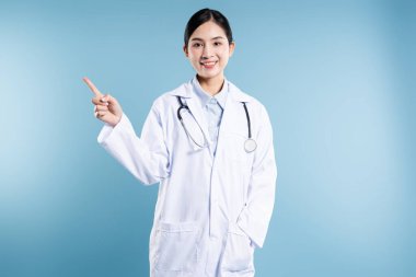 Steteskoplu beyaz önlüklü gülümseyen doktor, görünmeyen bir sağlık sigortası ayarına işaret ediyor.