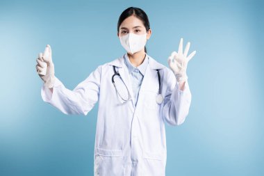 Beyaz önlüklü ve eldivenli bir kadın doktor mavi arka planda 