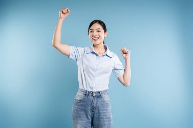 Mavi bir arkaplanda kollarını kaldırmış neşeli bir kadın neşeli ve muzaffer bir tavır sergiliyor.