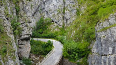 Aerial drone view above a bridge winding through vertical stone walls of a sharp, steep canyon located in Sohodol Gorges. Carpathia, Romania.