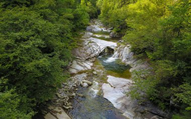 Drone photo above a mountain river forming stepped cascades and ponds when flowing through eroded large stone pieces. Latorita Mountains, Carpathia, Romania.
