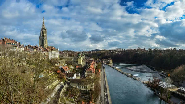 Panorama shot over a bridge taken in Bern, Switzerland. Old historic buildings can be seen along the canal. 