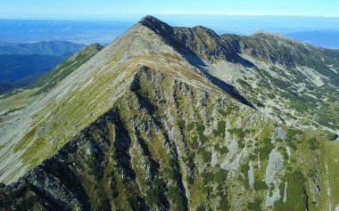 Aerial drone panorama above the high summits of Retezat Mountains and an alpine cauldron populated by mountain pines. Carpathian Mountains, Romania.