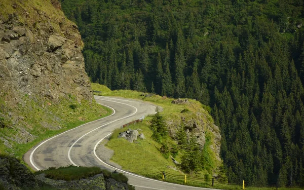 Transfagarasan road winding in Fagaras Mountains high altitude crests. A sinuous curve bypasses a sharp cliff and winds near a steep abyss. Carpathia, Romania.
