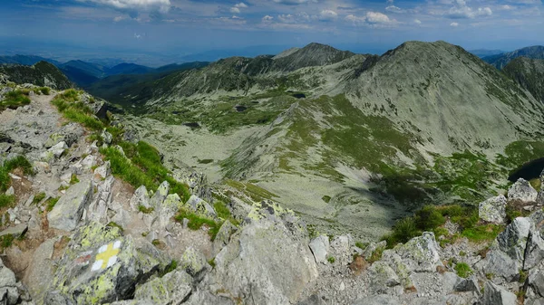 Panorama above the high summits of Retezat Mountains and the glacier lakes and cauldrons beneath them. High altitude landscape with rocky mountains and alpine pastures. Carpathia, Romania.
