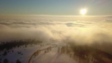 Bulutların yüksekliğinde bir dron uçurmak. Film, güneş batarken bulutların hareketini ve ön planda oluşunu yakalar. Kış mevsimi, aşağıdaki yol karla kaplı. Karpatya.